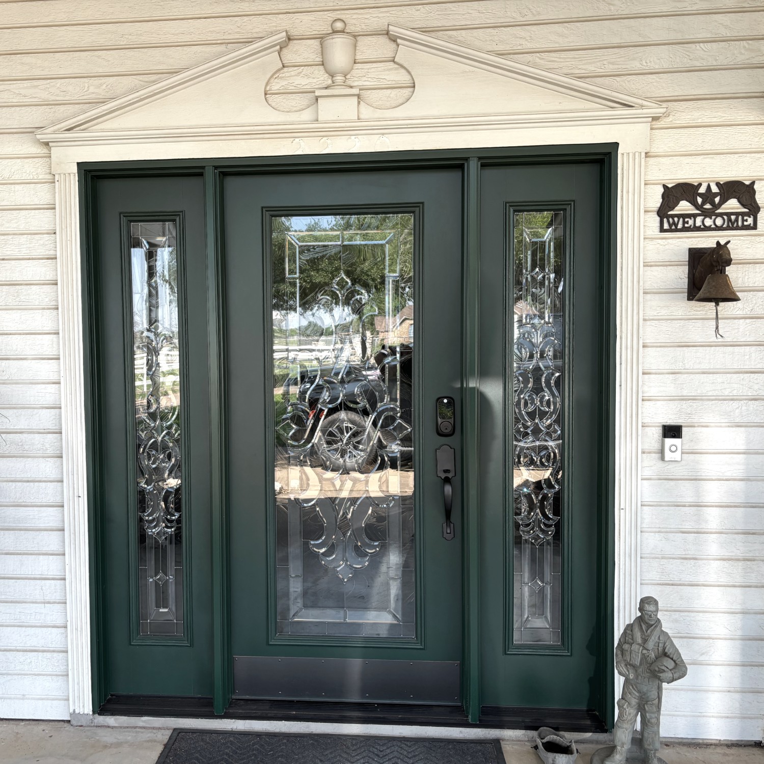An Ensemble entry door with dual sidelights. The door is a dark green with black hardware and white wood trimwork.