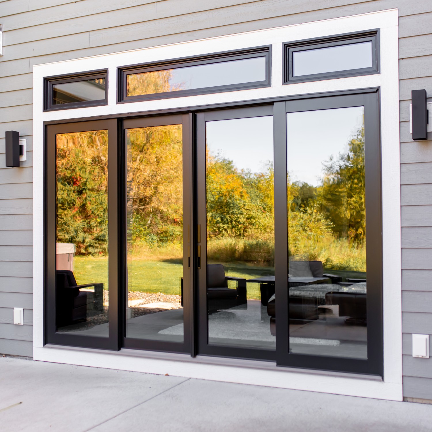 Four a-series contemporary sliding doors in black. Three transom windows above the doors add more light.