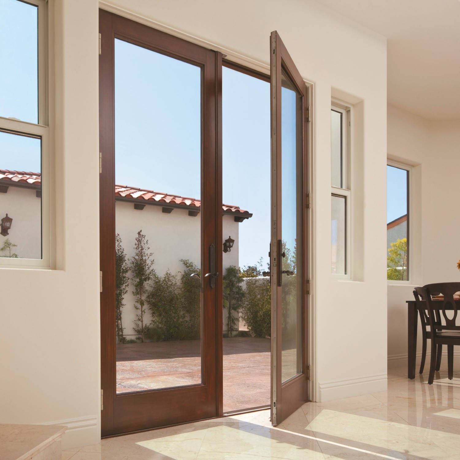 A hinged inswing french door with natural wood finish and a dark stain. The home is a southwest style.