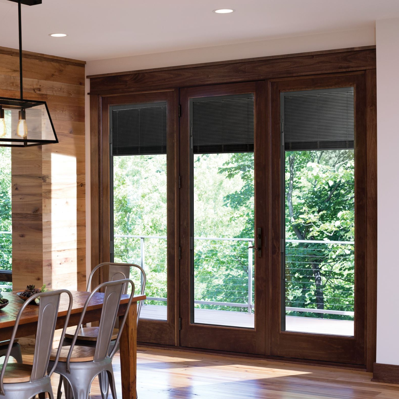 A mix of inswing and fixed a-series french doors. These have a dark wood stain and a traditional style. The a-series doors have blinds between the glass.