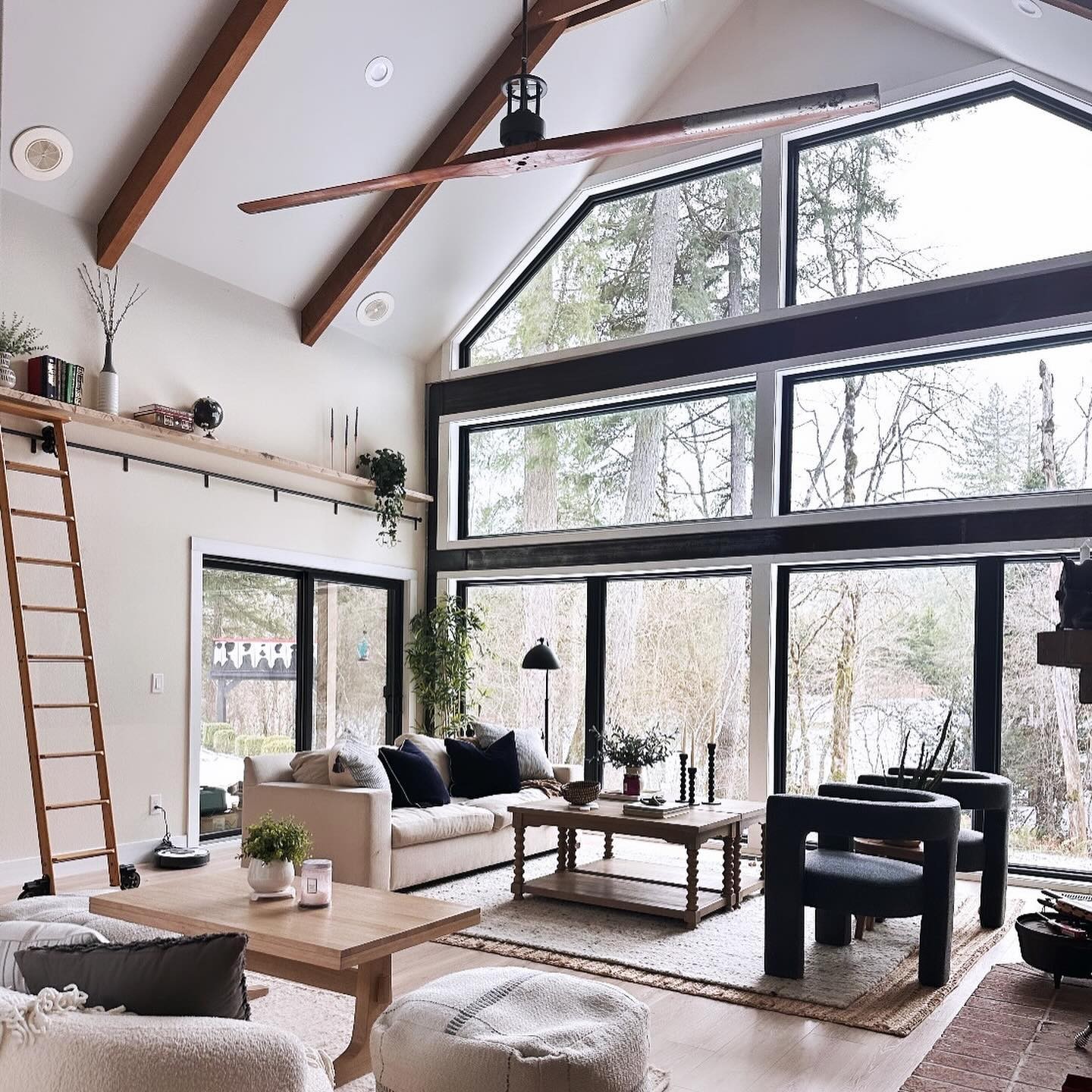 A large great room with high ceilings. There are patio doors with picture windows above, and specialty windows on top of that.