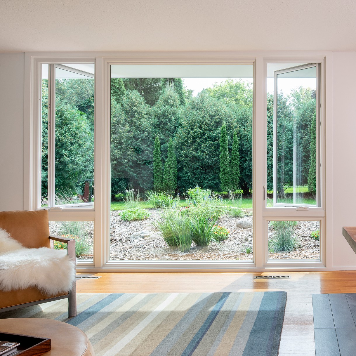 A mid-century modern living and dining room. There is a very large picture window looking out to the back yard.