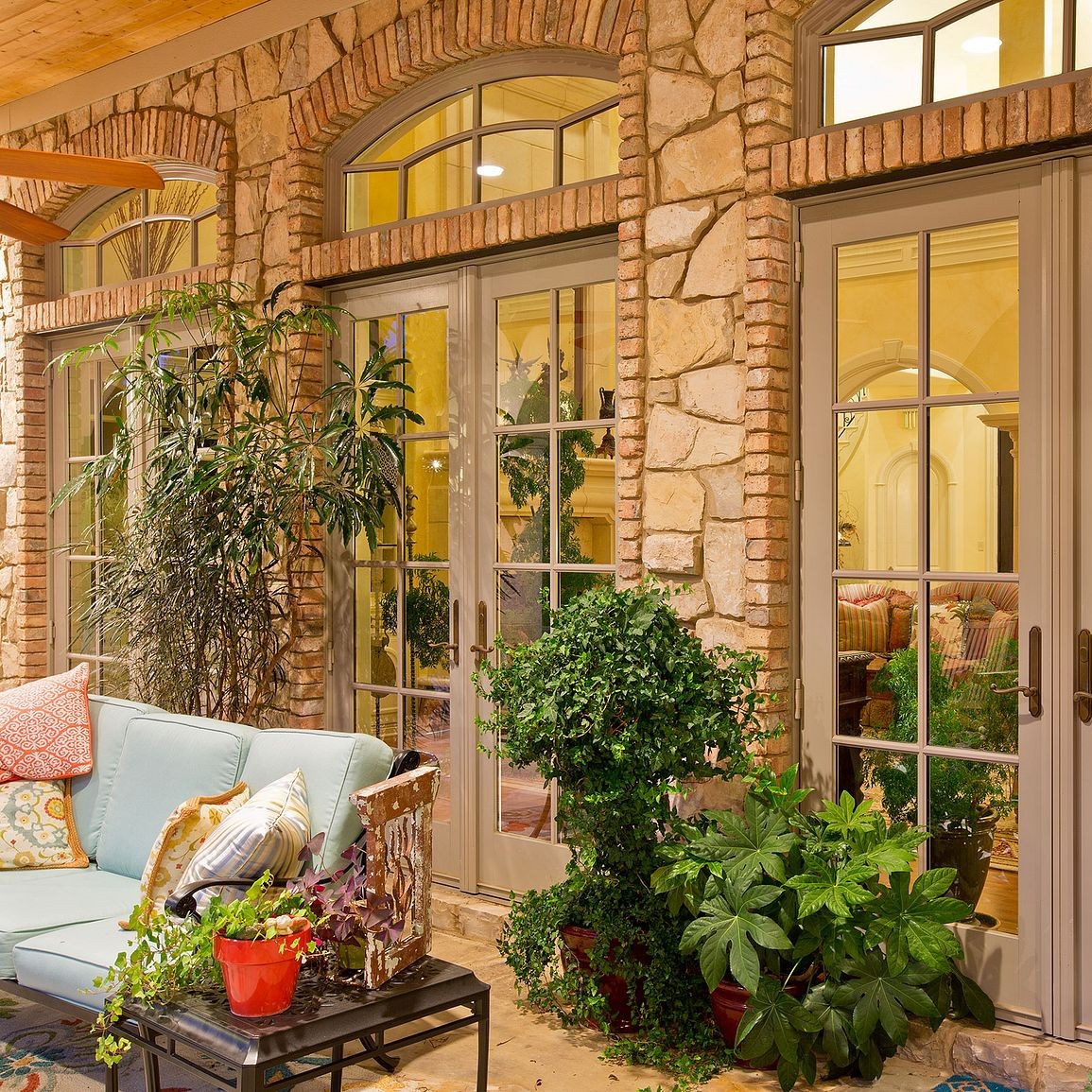 A home with stone facade. There are three sets of double patio doors. Each set is topped by an equal leg arch with custom grilles. The windows and doors are sandtone color.