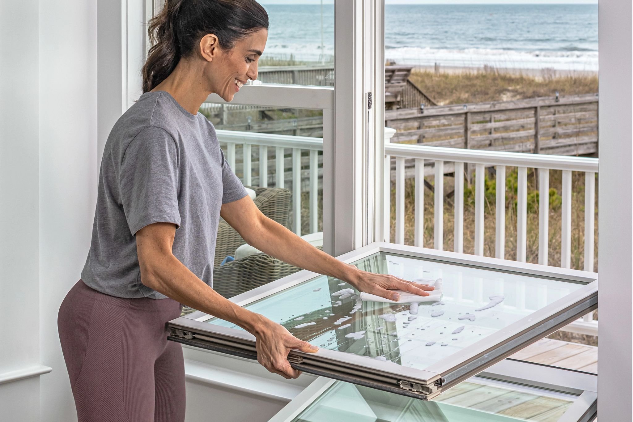 A nice lady diligently cleans a double-hung window. It is a much easier job because it tilts into the house and you can wash from inside.