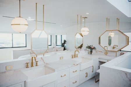 The bathroom area in the primary suite in Breegan Jane's california beach house. It is all white with gold fixtures.
