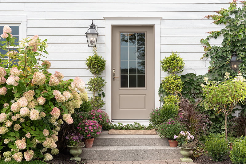 A white house featuring a front door and decorative potted plants on either side.