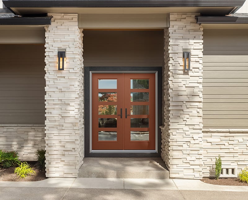 A front door framed by a stone wall on one side and a brick wall on the other, showcasing contrasting textures.