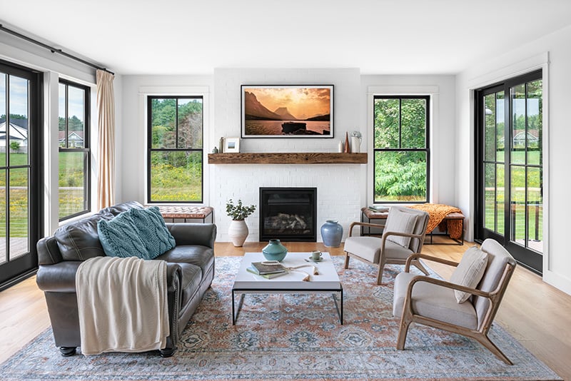 White living room with a wood floor. Black windows let lots of natural light in on all sides.