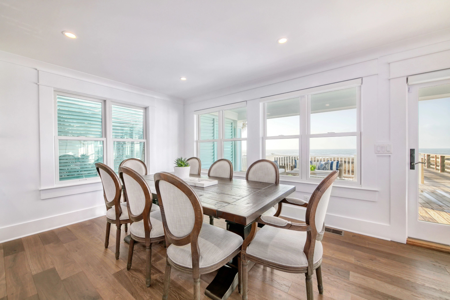 A dining room featuring hardwood floors and Renewal by Andersen's composite Windows, with a view of the ocean outside
