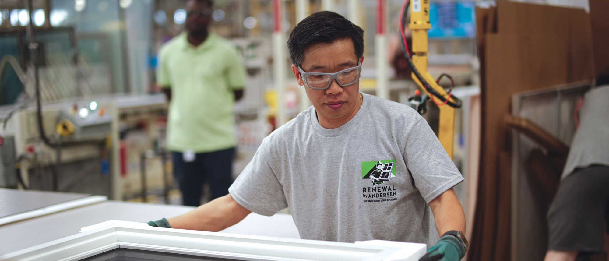 A Renewal by Andersen employee at inspecting a window at a manufacturing plant